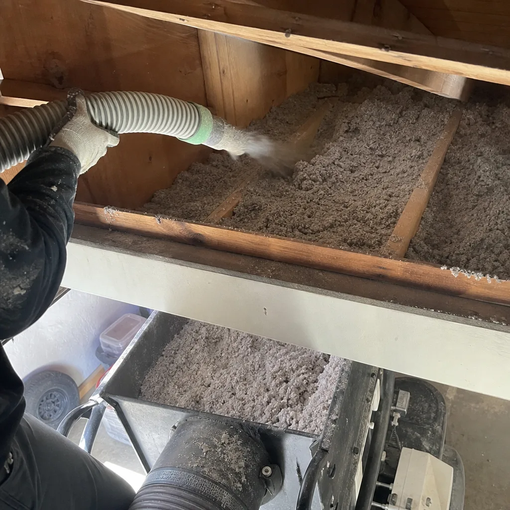 Contractor installing blown-in cellulose insulation in an attic